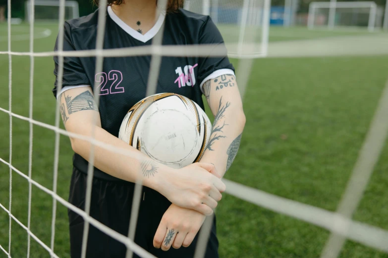 female soccer player holding ball behind the goal