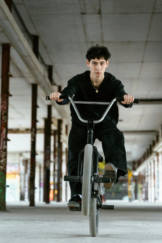 man riding bike in parking garage area with cement floor