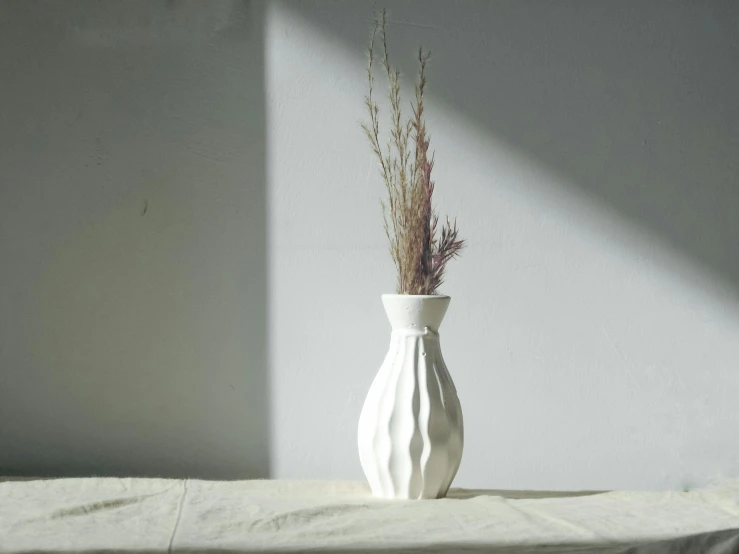 a white vase with a plant inside of it