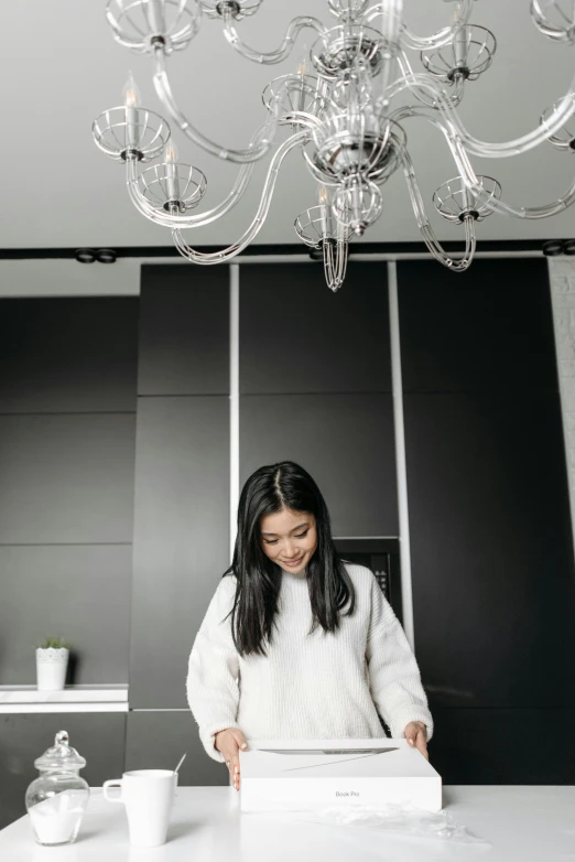 a woman in a sweater stands in front of a white cake