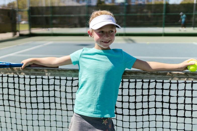 young female tennis player leaning on a net