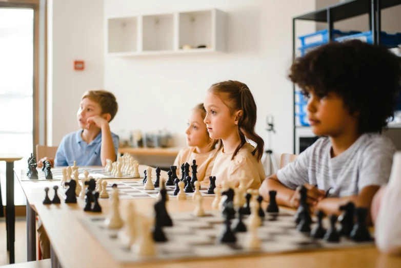 children sitting at a table playing chess together