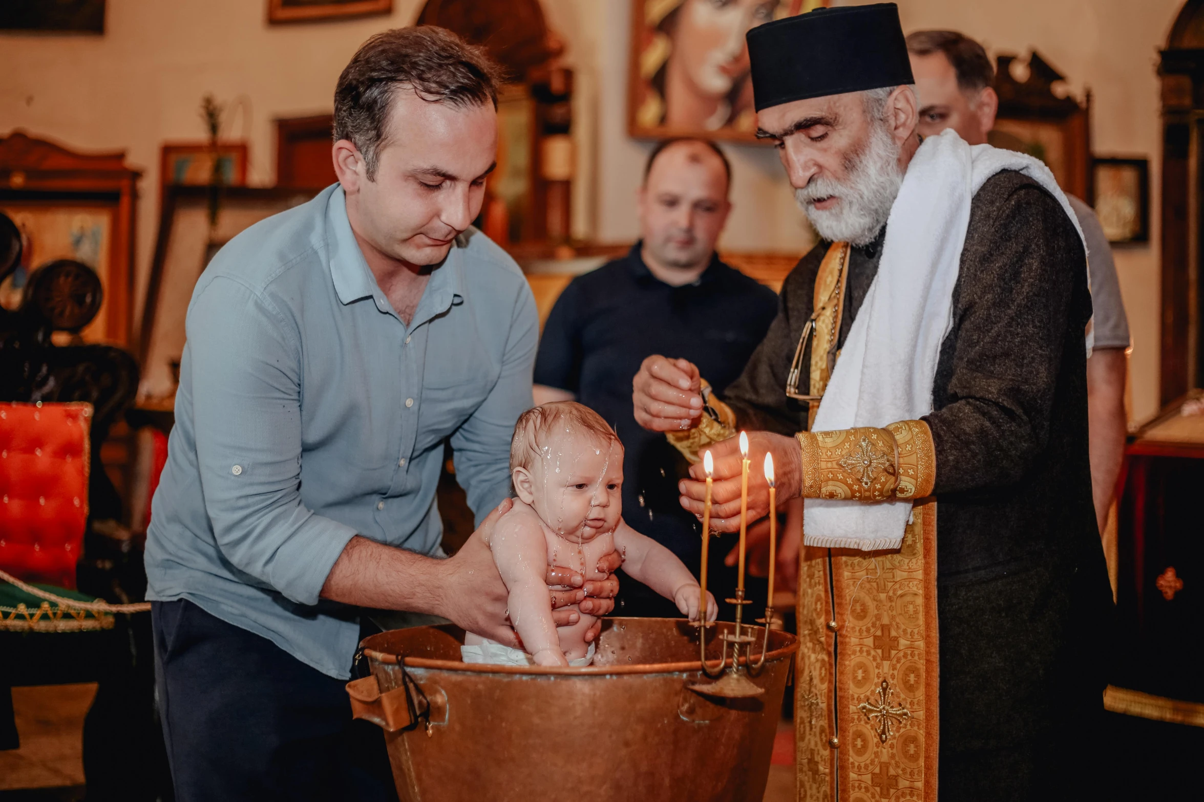 two men looking at the baby who is in a bath tub with candles