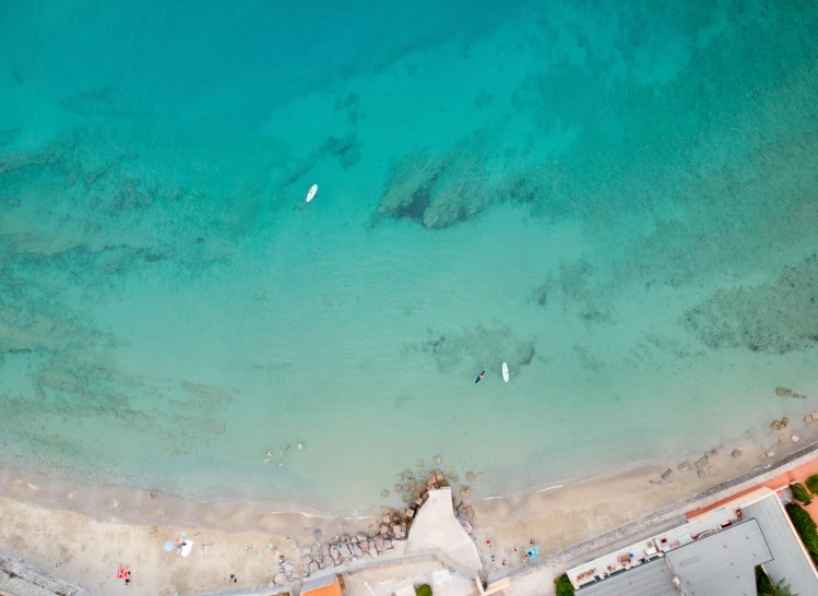 several boats anchored on the water in front of a beach