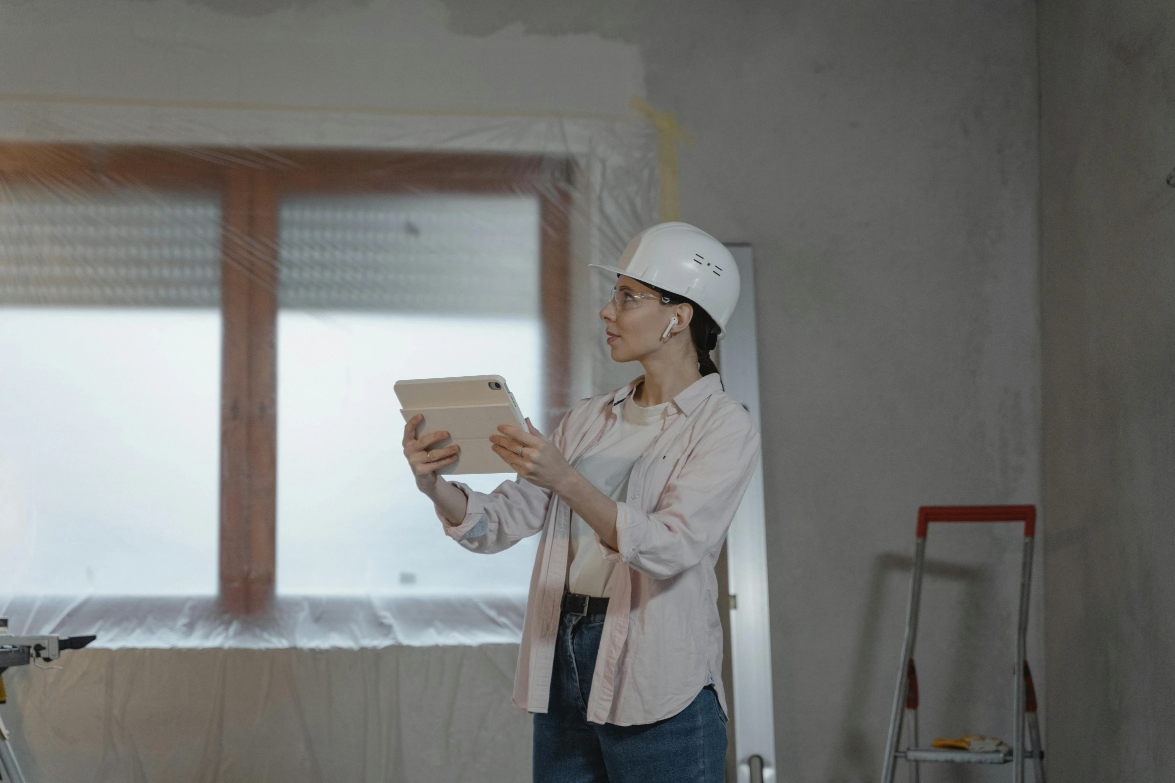 a woman in a hardhat stands reading a book