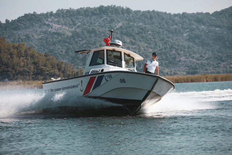 a small boat driving on the water with people standing on the front