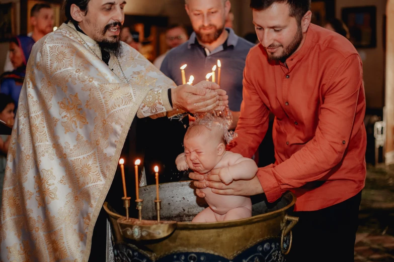 three men are lighting candles on the small baby