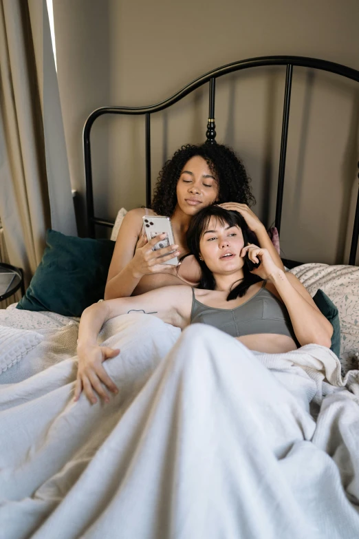 two women laying on a bed next to each other
