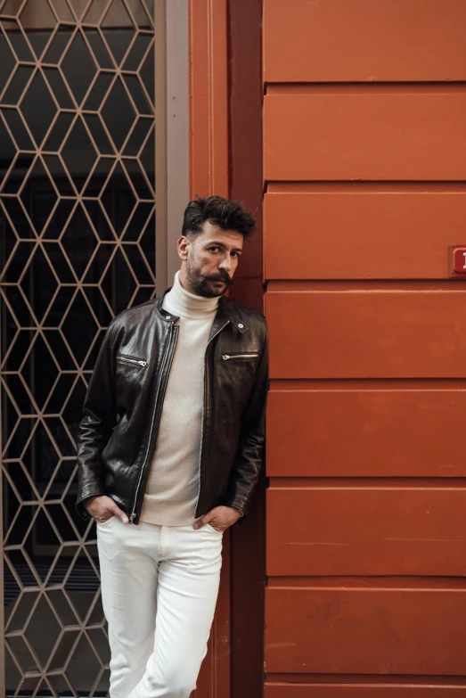 the man in leather jacket standing by red door