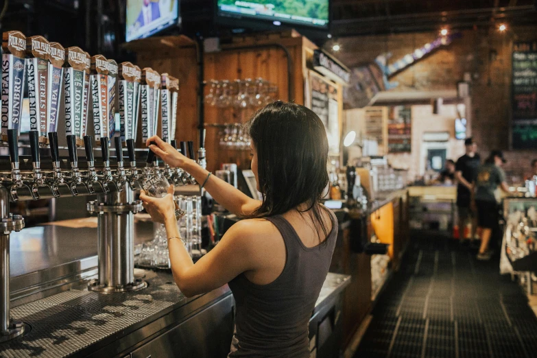 woman in tank top is pouring a drink at a bar
