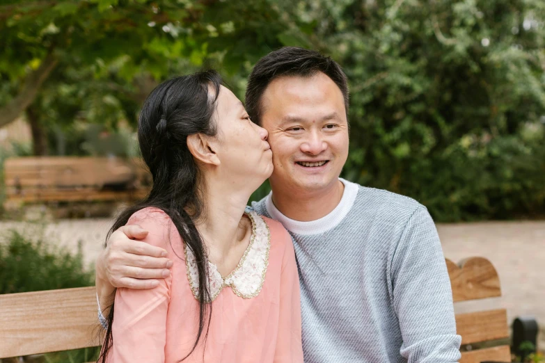 a man and a woman who are cuddling on a bench