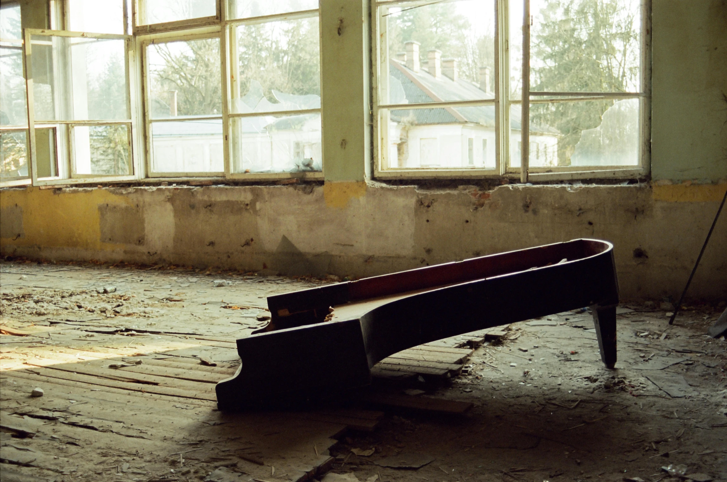 a bench sits in a ruined room in front of large windows