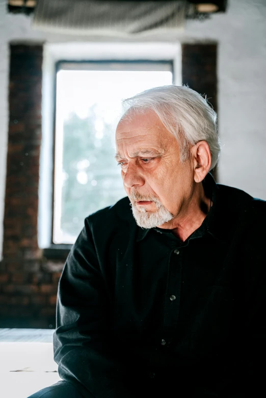 a man sitting on a desk next to a window