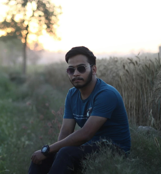 a man sitting on top of a hill next to grass