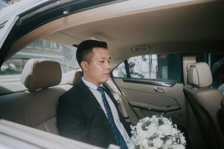 a man sitting in the back of a car holding a bouquet of flowers