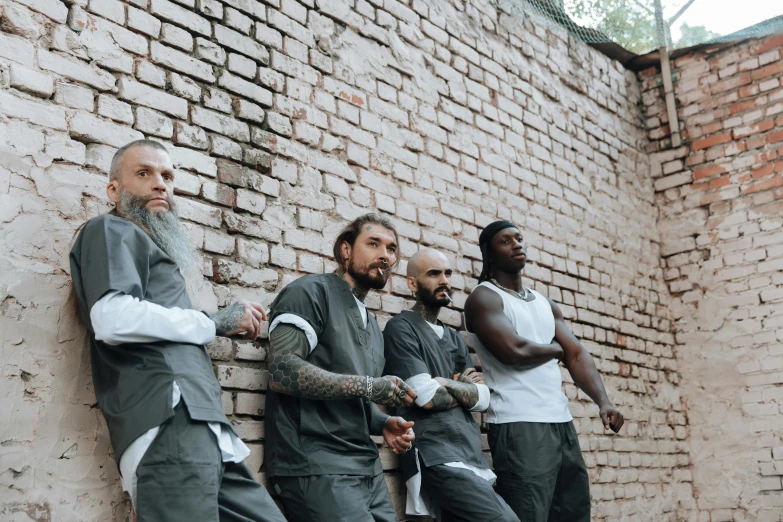 a group of men standing next to a brick wall