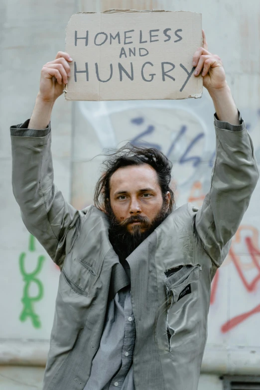 a person holds up a sign that reads homeless and hungry