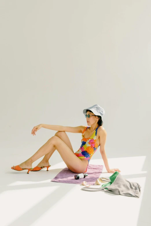 a woman wearing a colorful one piece swimsuit sitting on a towel