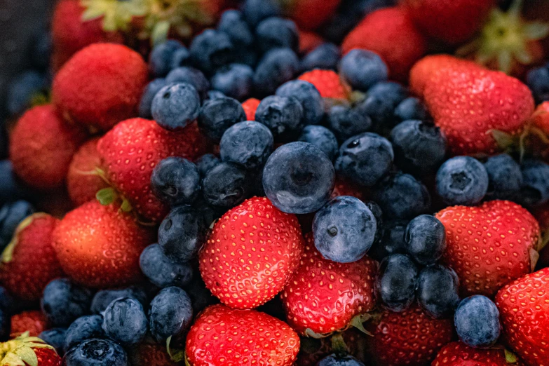 a closeup of blue and red fruit sitting on the counter