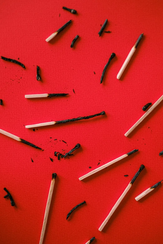 a red background with a variety of matches sticks and broken toothbrushes