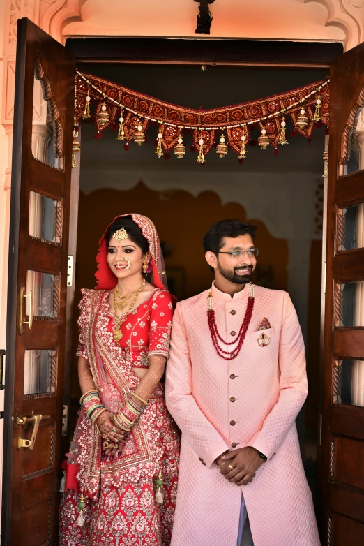 a man and a woman in traditional indian dress are standing at the doorway