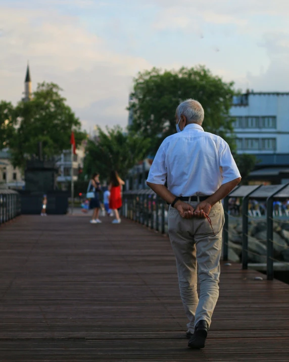 an older man walking on a wooden pier
