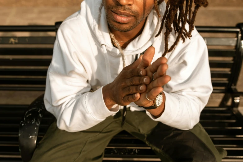 a man with dreadlocks sits on a bench