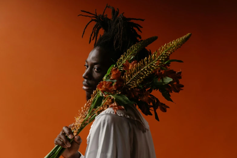 man wearing dreadlocks and holding large bouquet of flowers