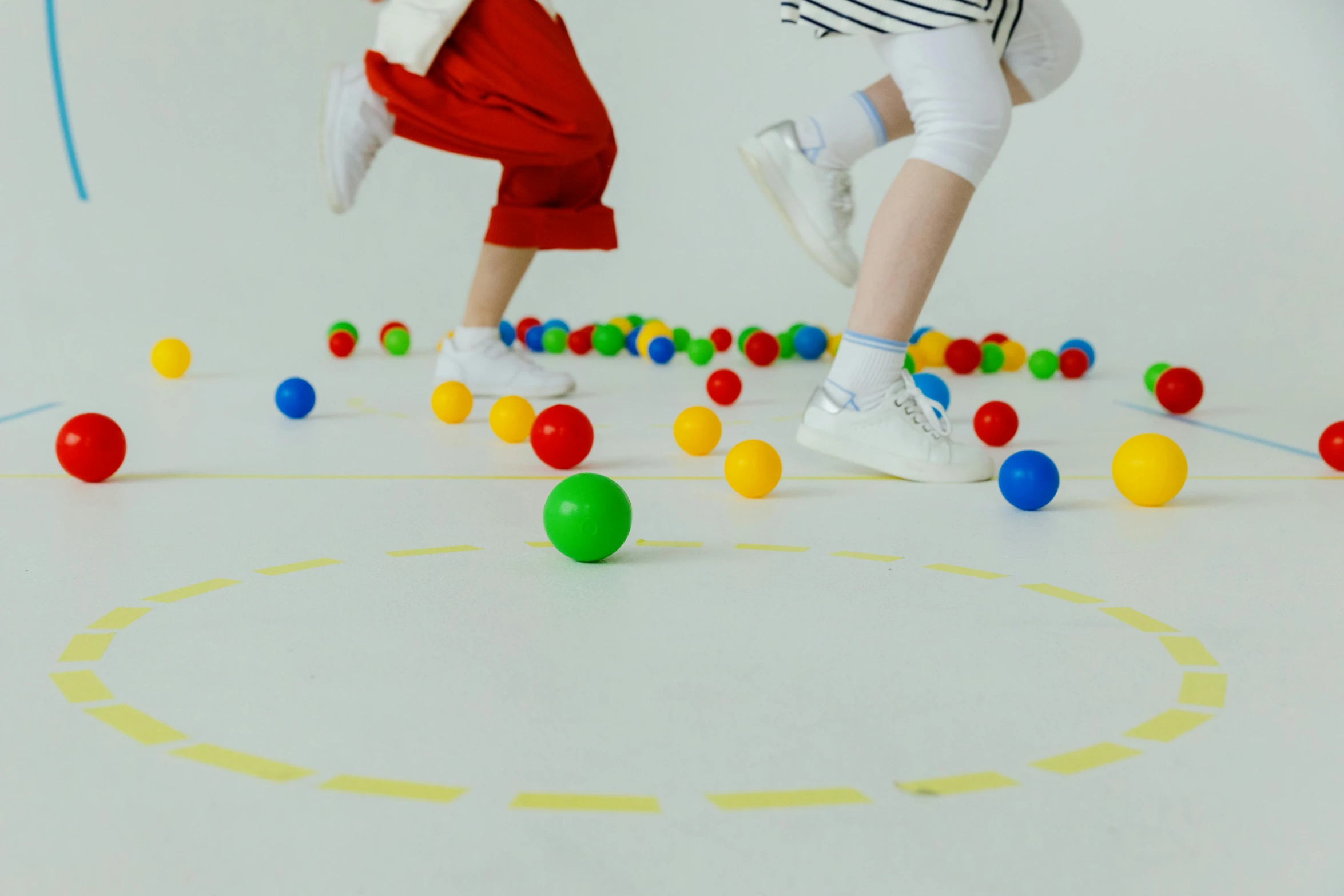 two children are playing on a floor with balls