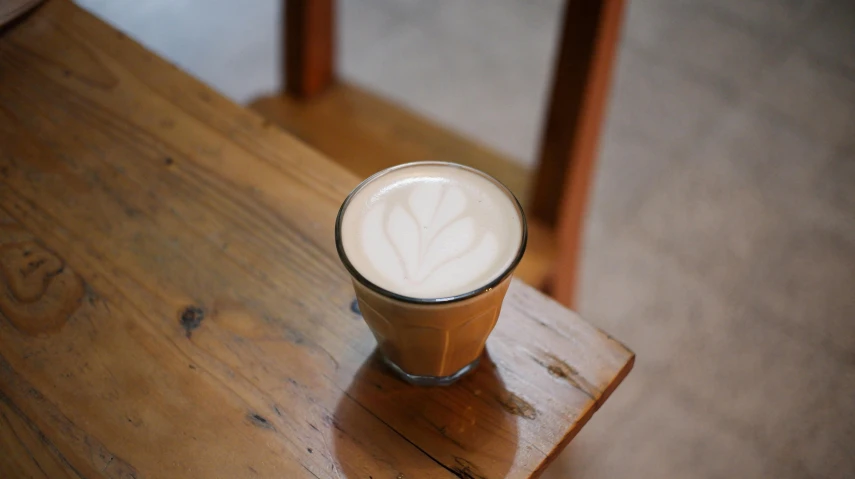 a tall glass of ice cream soda sitting on top of a wooden table