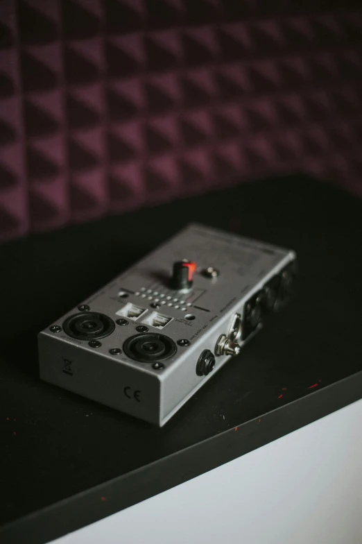 an audio device sitting on a table next to a red curtain