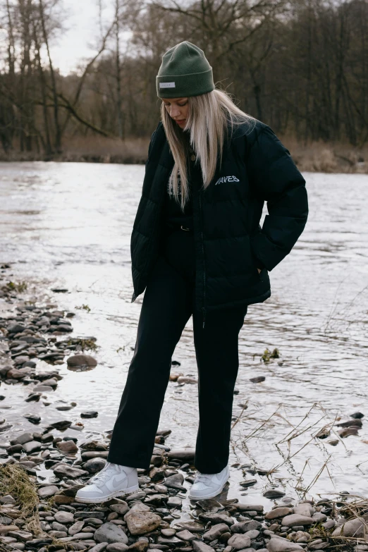 the young person stands on the rocks in front of a river