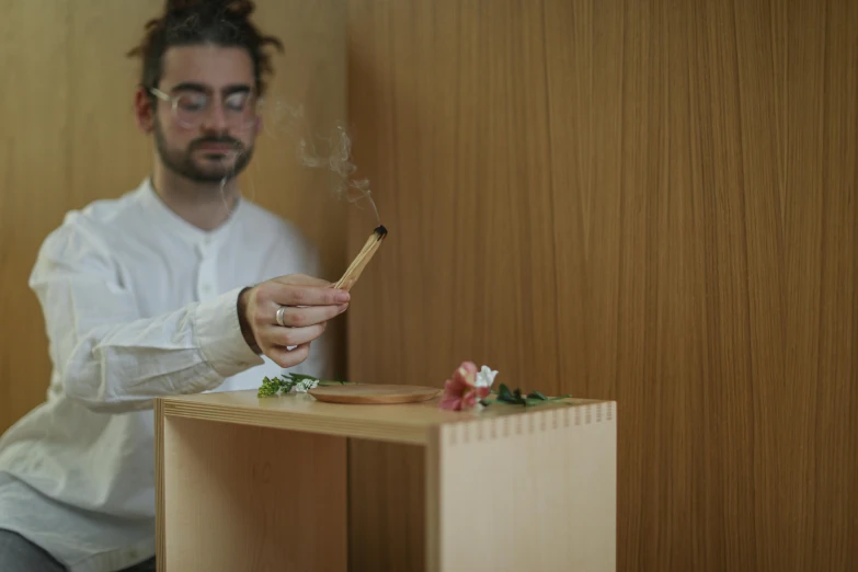 a person holding a match in their hand and sitting at the desk