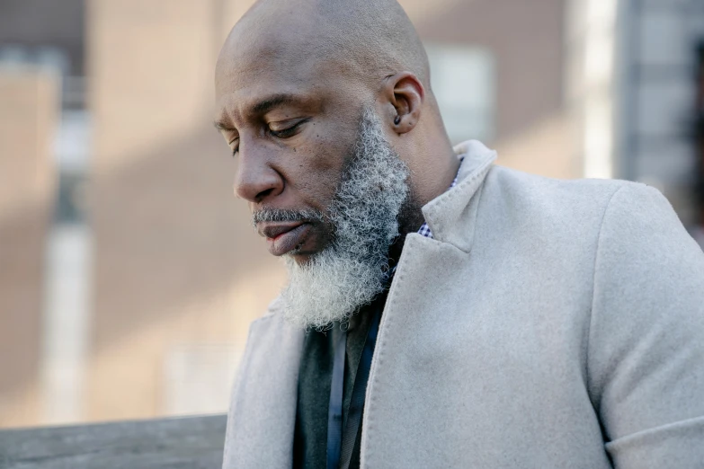 bald man with beard and black tie looking down