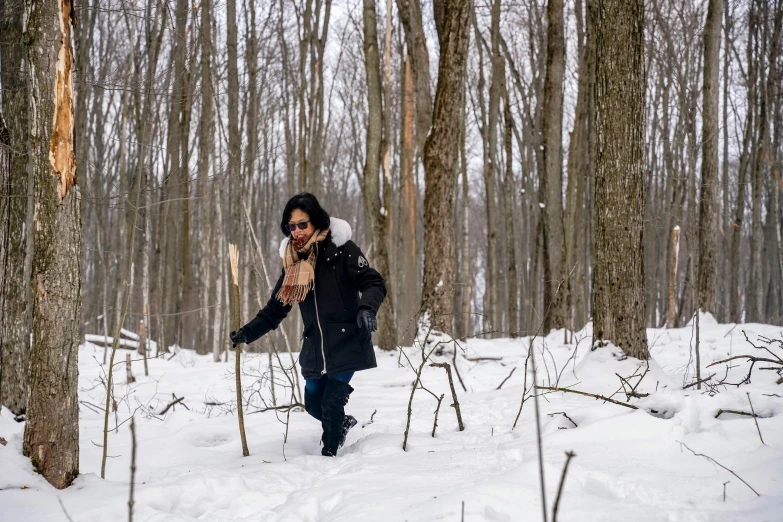 a woman standing in a snowy wooded area on her cell phone