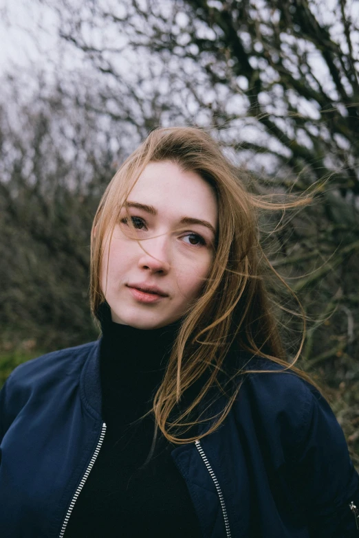 the girl is standing on a hill looking directly into the camera