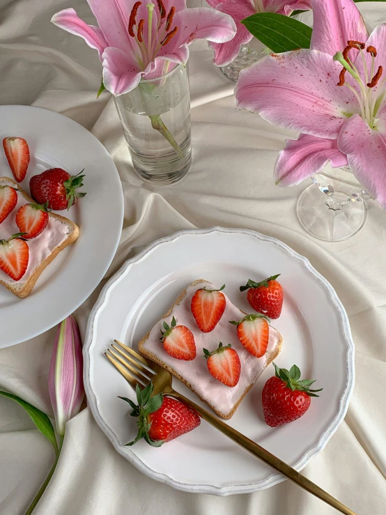 two white plates with slices of cake and strawberries