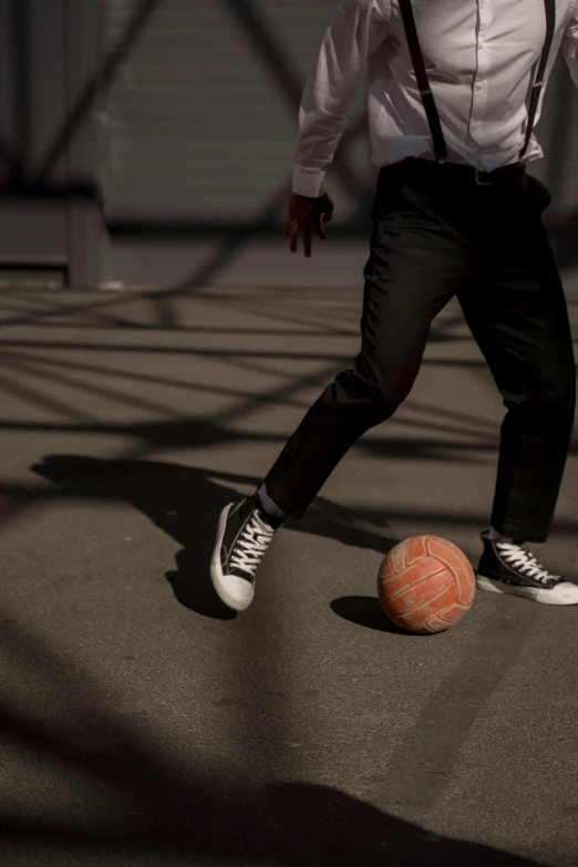 a man in a shirt and tie kicking a ball with his feet