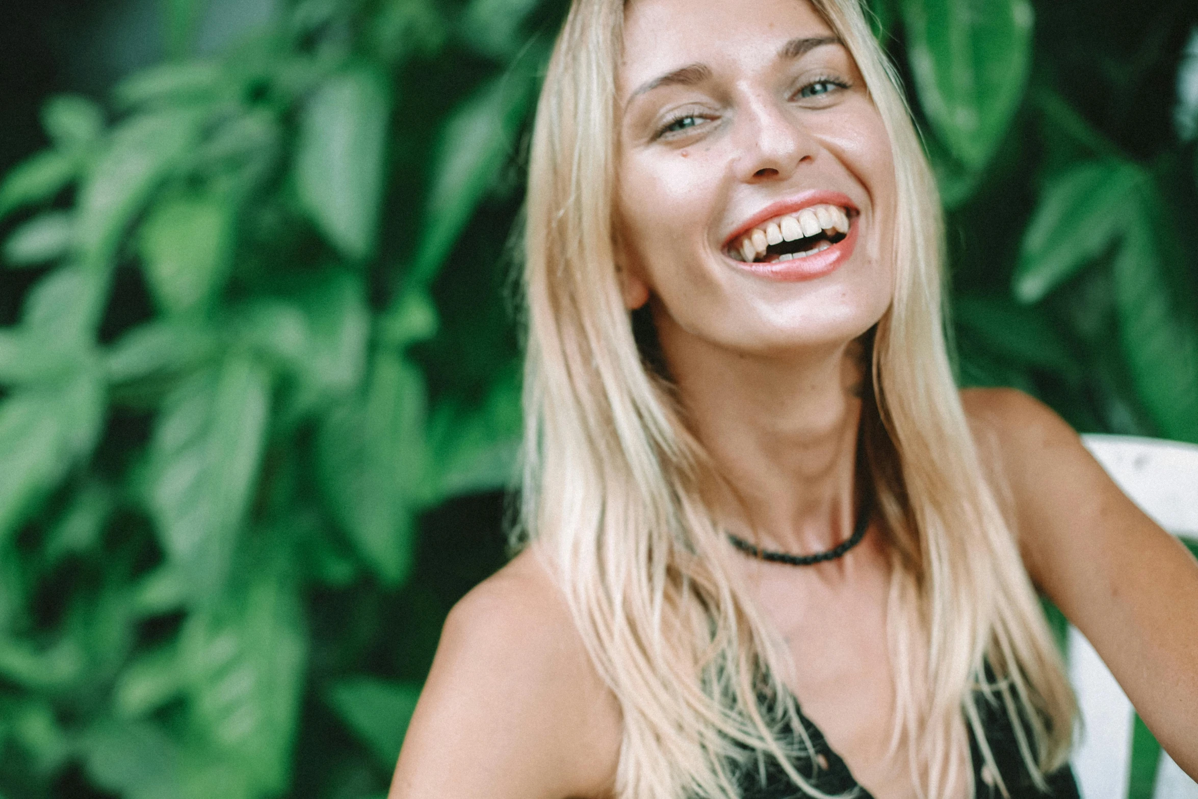 a woman smiles while sitting on a chair outside