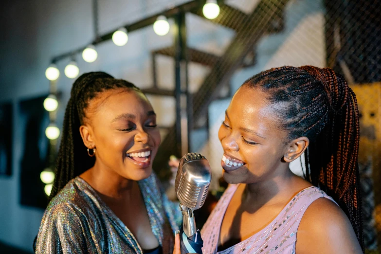 two women smiling and laughing together, while one woman holding a microphone