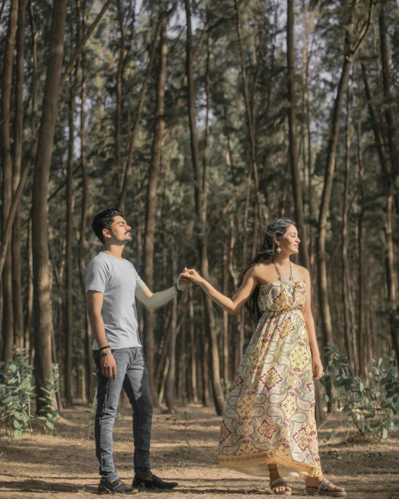 a man and woman standing in the middle of a forest