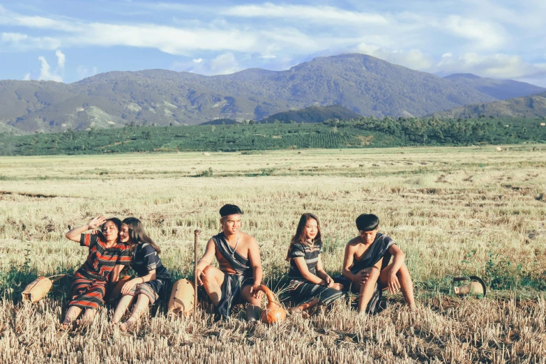 five people sitting in the middle of the grass