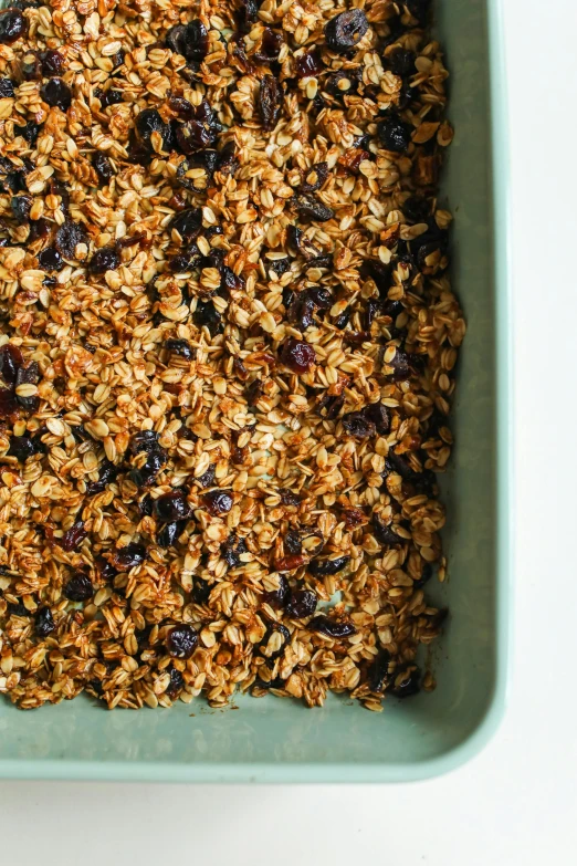 a square glass dish with granola and dried raisins