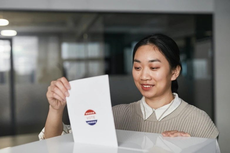the woman smiles as she puts the voting paper in her hand