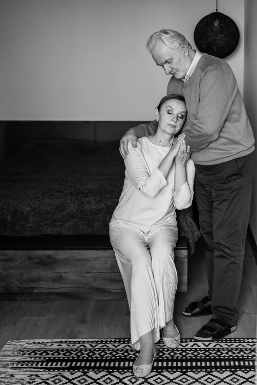 a black and white image of an old man giving a woman a hug