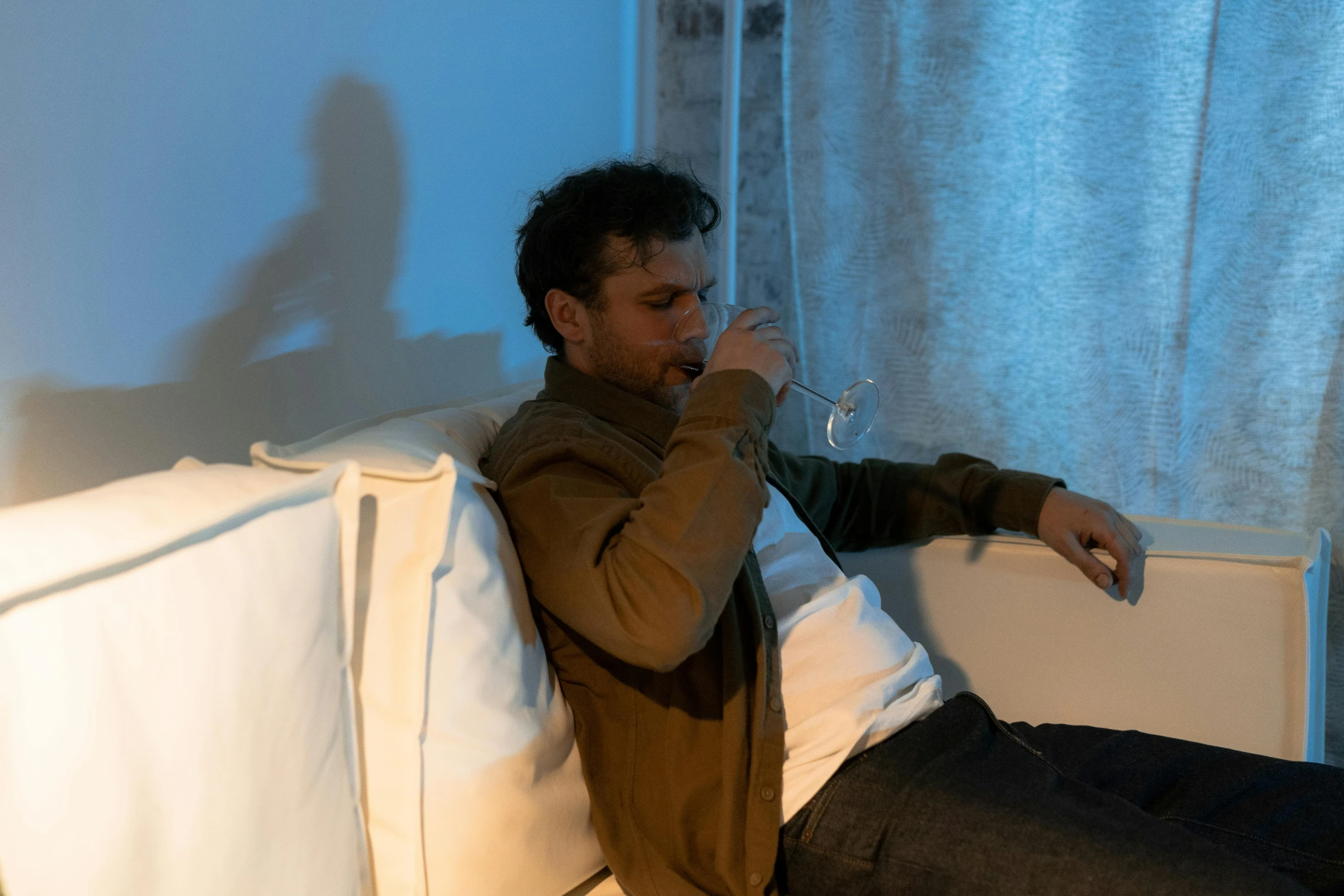 a man sitting on top of a couch while drinking wine