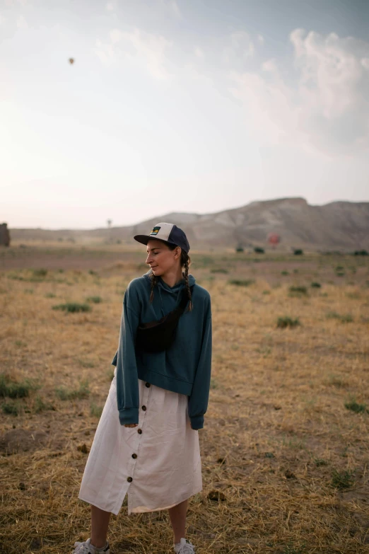 woman in hat and white dress standing in open field