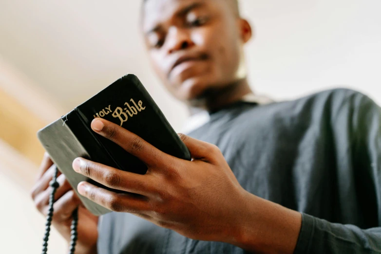 a man holding a small bible and using his hands