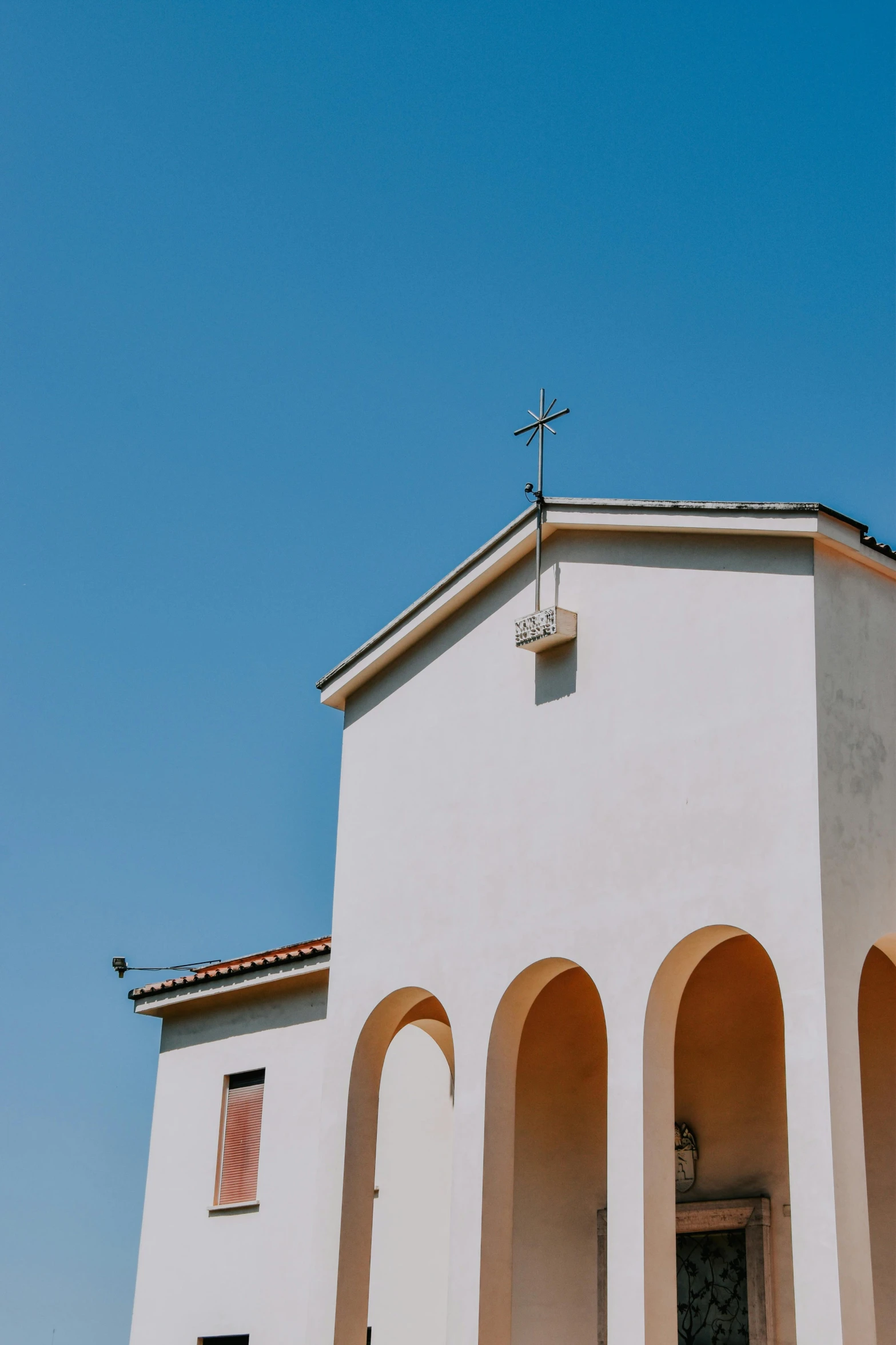 a cross is above an arched, white building