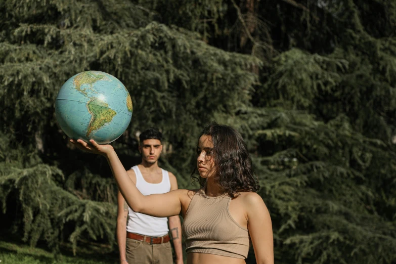 two young women and one man are holding an earth globe